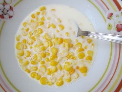 кукурузная каша на молоке в тарелке с ложкой